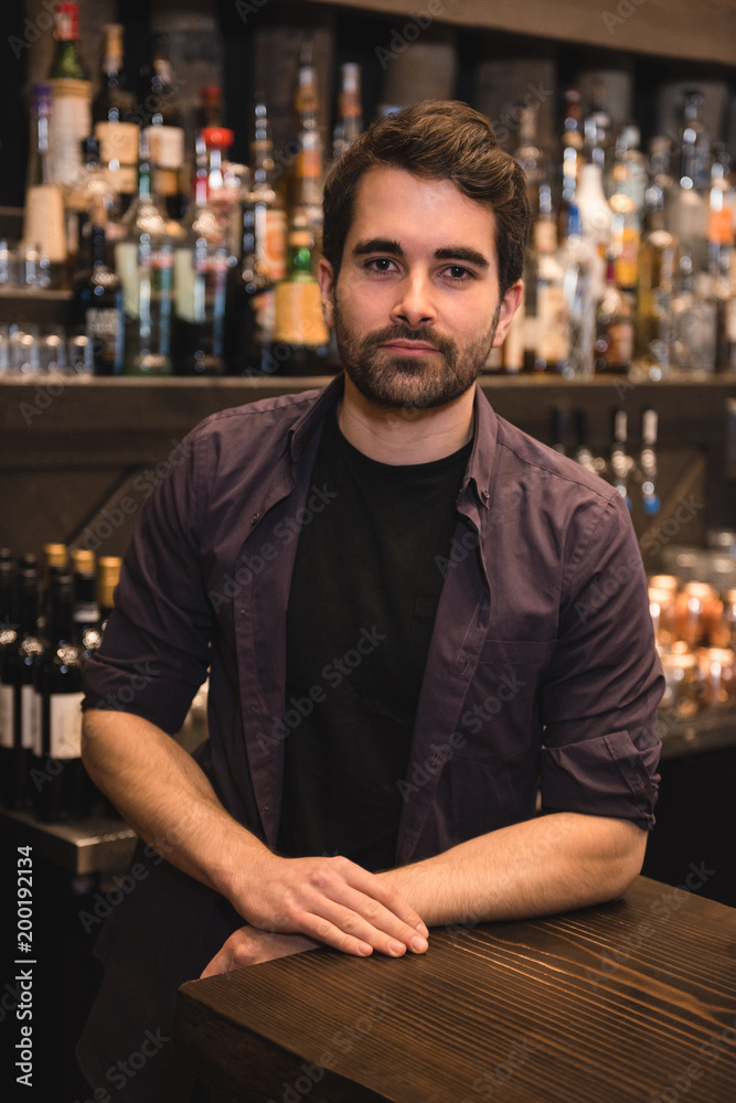 Confident bartender standing at bar counter Confident bartender standing at bar counter