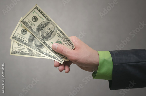Businessman hand is stretching a dollars money isolated on gray background. Financial help. Bribe and corruption. Bank loan. Giving money.