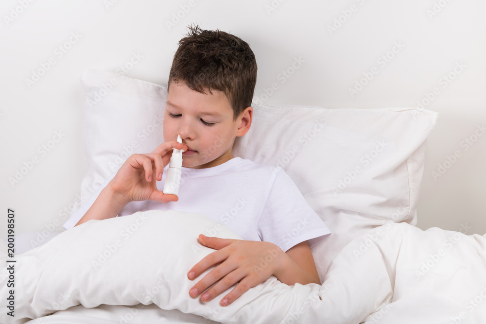 the boy in the bed hugs a teddy bear and sprinkles drops in the nose from the snot the boy in the bed hugs a teddy bear and sprinkles drops in the nose from the snot