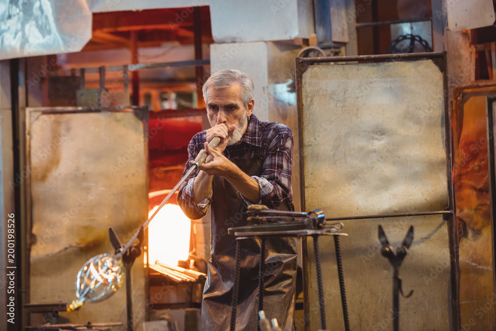 Glassblower shaping a glass on the blowpipe Glassblower shaping a glass on the blowpipe