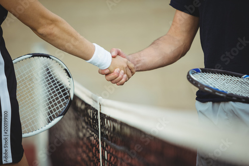 Close up of tennis players handshaking in sportsmanship at net