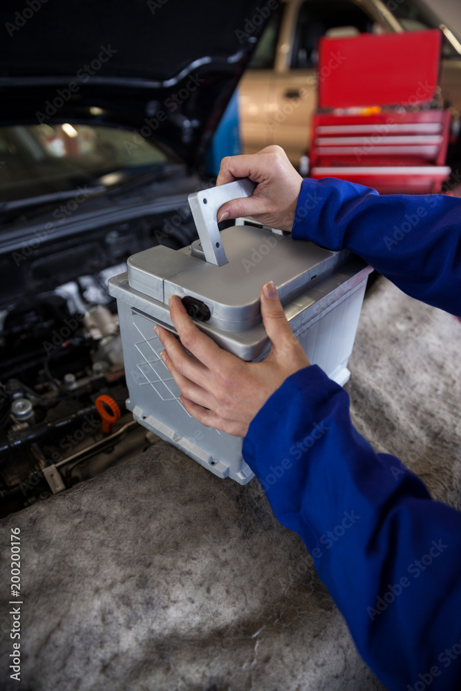 Mechanic removing car battery from car Mechanic removing car battery from car