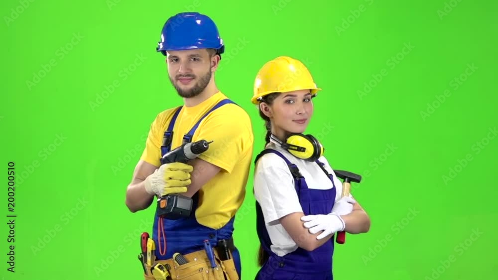 Builder standing a guy holding a drill, a girl hammer. Green screen. Slow motion Builder standing a guy holding a drill, a girl hammer. Green screen. Slow motion