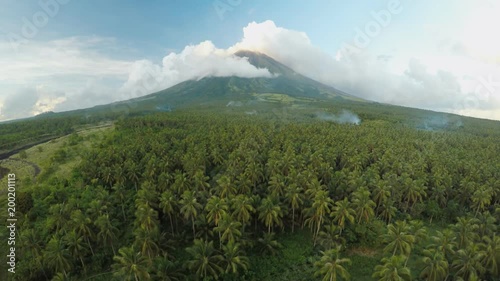 Mayon Volcano near Legazpi city in Philippines. Aerial view over the palm jungle and plantation at sunset. Mayon Volcano is an active volcano and 2462 meters high. photo