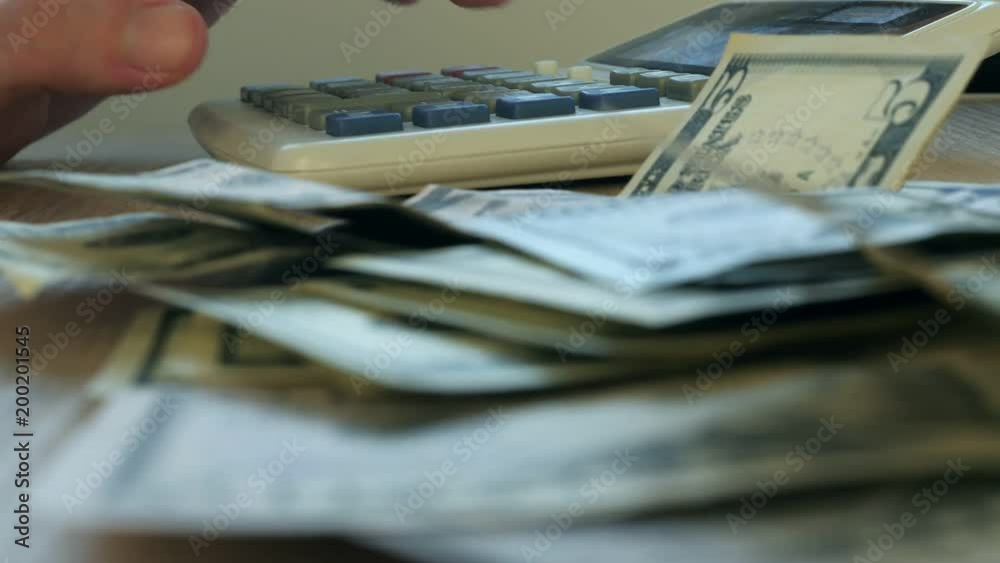 Hand typing on a calculator and dollar banknotes. Savings and home finances concept. Hand typing on a calculator and dollar banknotes. Savings and home finances concept.