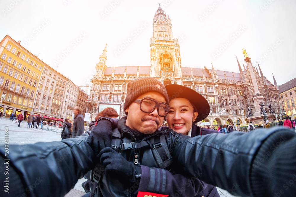 Obraz premium Young Couple Tourists taking selfie with mobile smartphone at the Marienplatz , a famous landmark in Munich, Germany