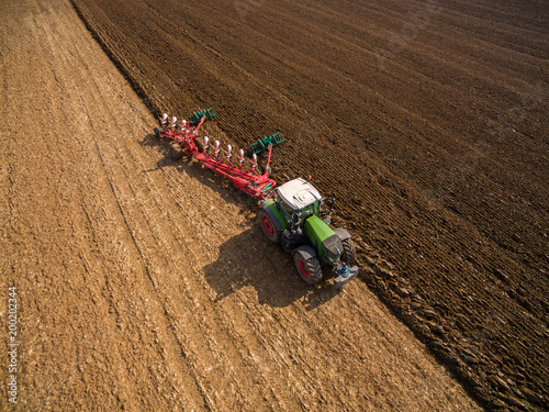 AERIAL : Tractor plowing a field - Tractor preparing the land for sowing in the spring