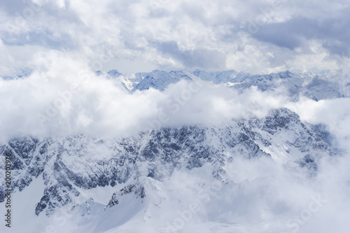 Schneebedeckte riesige Berge umgeben von wei  en Wolken in einsamer H  he.