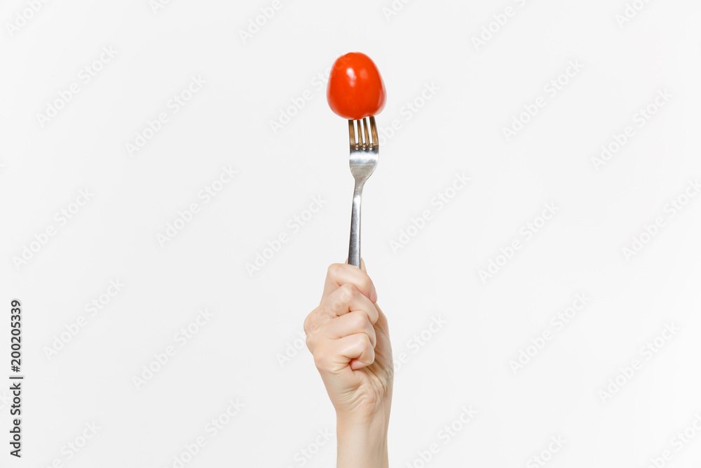 Close up female holds in hand red fresh tomato on fork isolated on white background. Proper nutrition, vegetarian food, healthy lifestyle, vegetable vegan concept. Advertising area with copy space