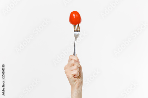 Close up female holds in hand red fresh tomato on fork isolated on white background. Proper nutrition, vegetarian food, healthy lifestyle, vegetable vegan concept. Advertising area with copy space