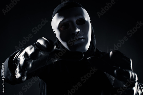 Man in mask reaching to the camera with his hands
