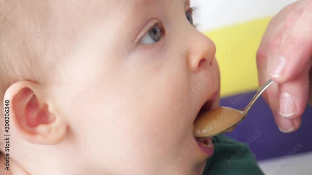 Baby eats puree from spoon, slow motion