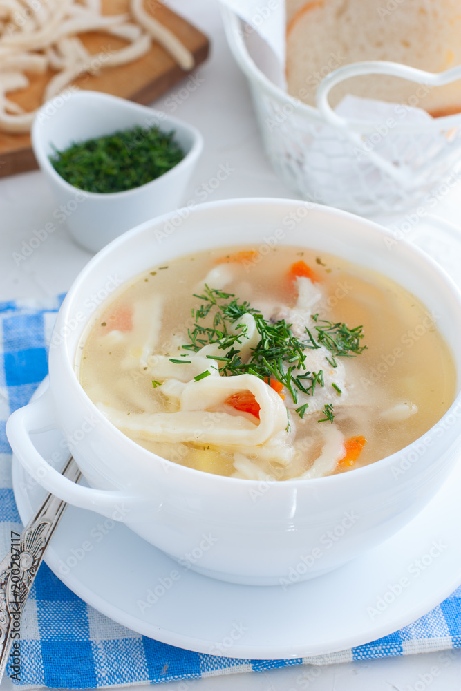 Hot homemade soup on chicken broth with homemade noodles in a white cup, selective focus Hot homemade soup on chicken broth with homemade noodles in a white cup, selective focus
