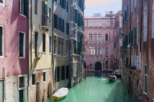 Gondola in a narrow water canal between buildings in Venice