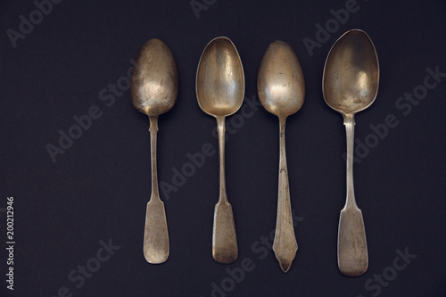 set of antique silver spoons on a dark background © akintevs