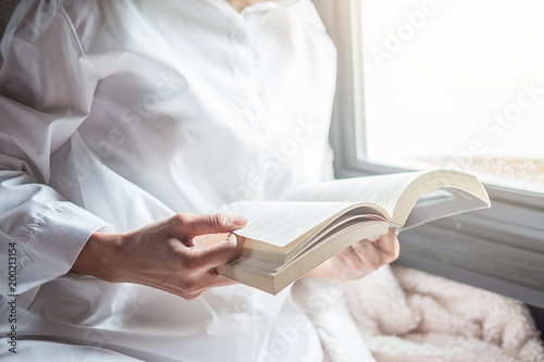 Reading a book. Beautiful female sitting on the bed and reading a book in her hands. Morning with a book in their hands.vintage color,selective focus