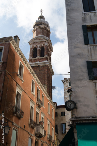 Exterior of apartment buildings with old clock, balconies and tower in Venice, Italy