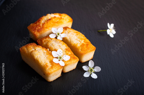 Foto Food concept mini French almond cake financier on black slate stone with copy sp