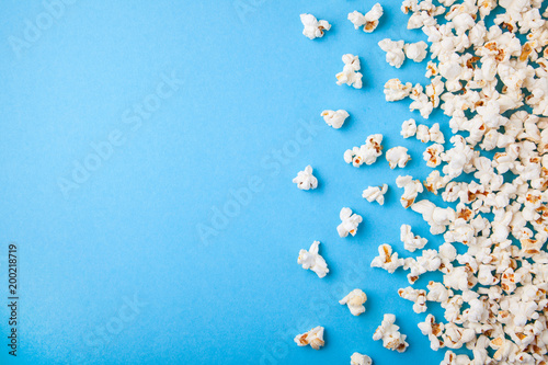 Popcorn scattered on blue background. Copy space for text