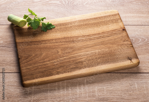 Wooden kitchen cutting Board on wooden background with greenery.