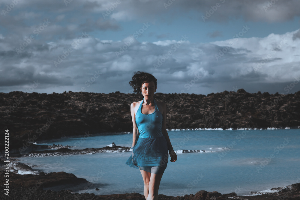Dark haired model is posing with a blue lagoon on a background