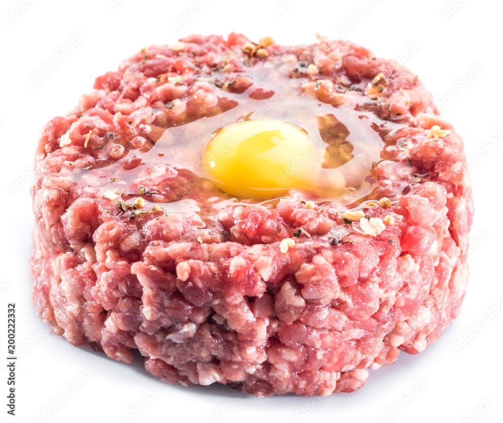Ground cutlet or raw hamburger with quail egg yolk and seasonings on white background. Close-up. Ground cutlet or raw hamburger with quail egg yolk and seasonings on white background. Close-up.