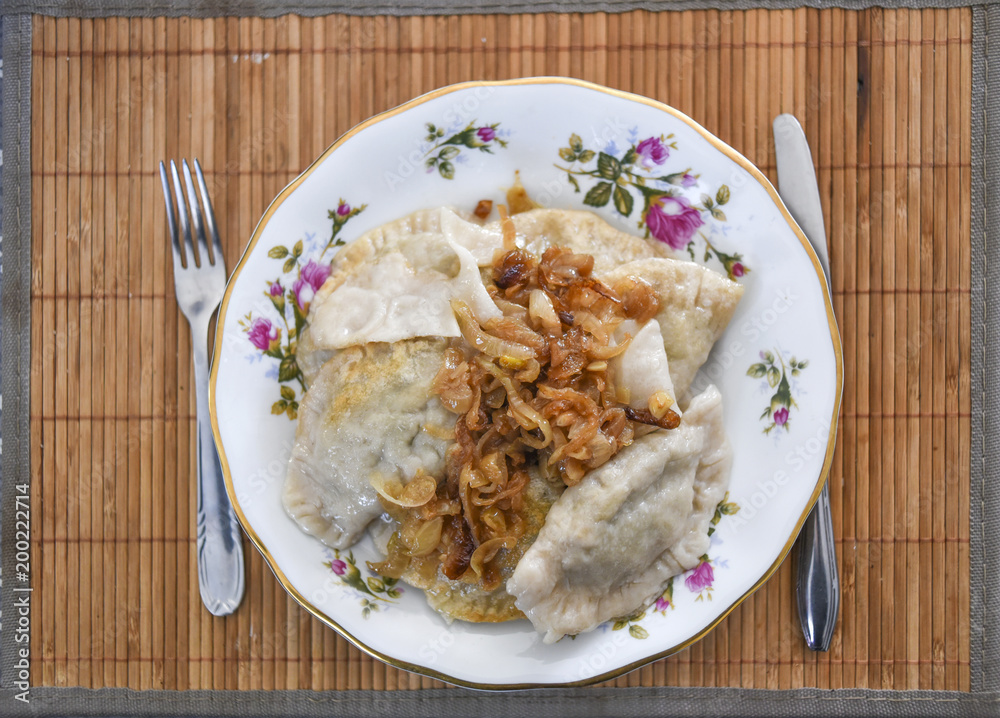 Dumplings with onions on plates, a traditional dish of Polish cuisine. Dumplings with onions on plates, a traditional dish of Polish cuisine.