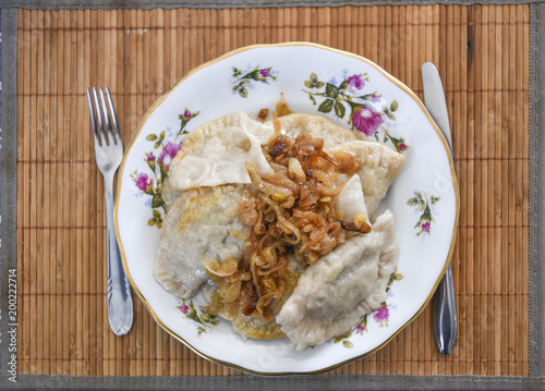 Dumplings with onions on plates, a traditional dish of Polish cuisine.
