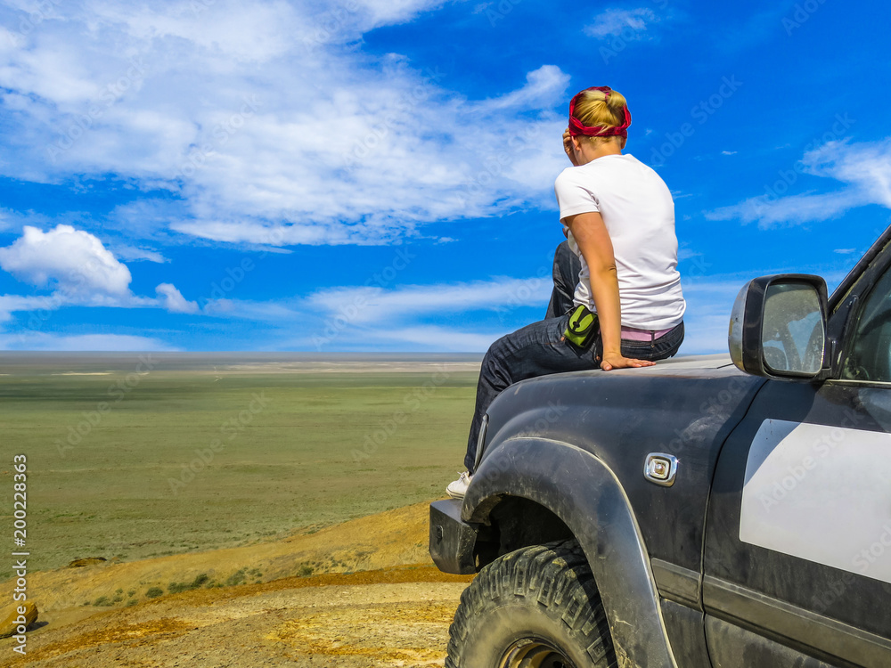 Young girl sitting back on the hood of a big car suv. Off-road travel  background. Desert Stock Photo | Adobe Stock