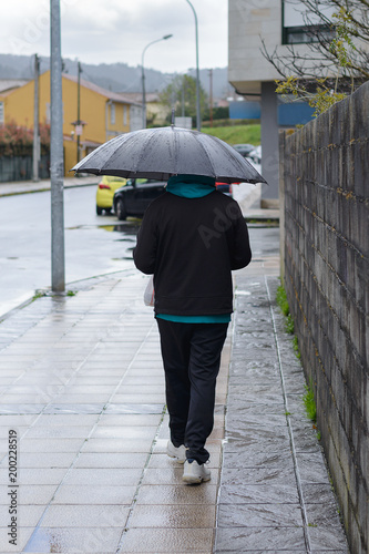 man in sports suit with umbrella outdoors  rear view