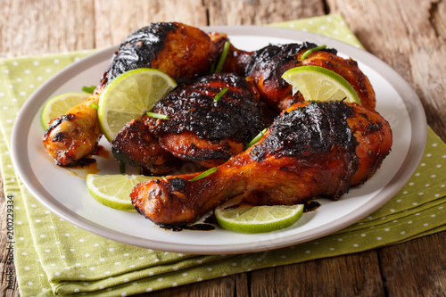 Photography Hot spicy grilled chicken drumstick with lime and green onion close-up on a plate on a table