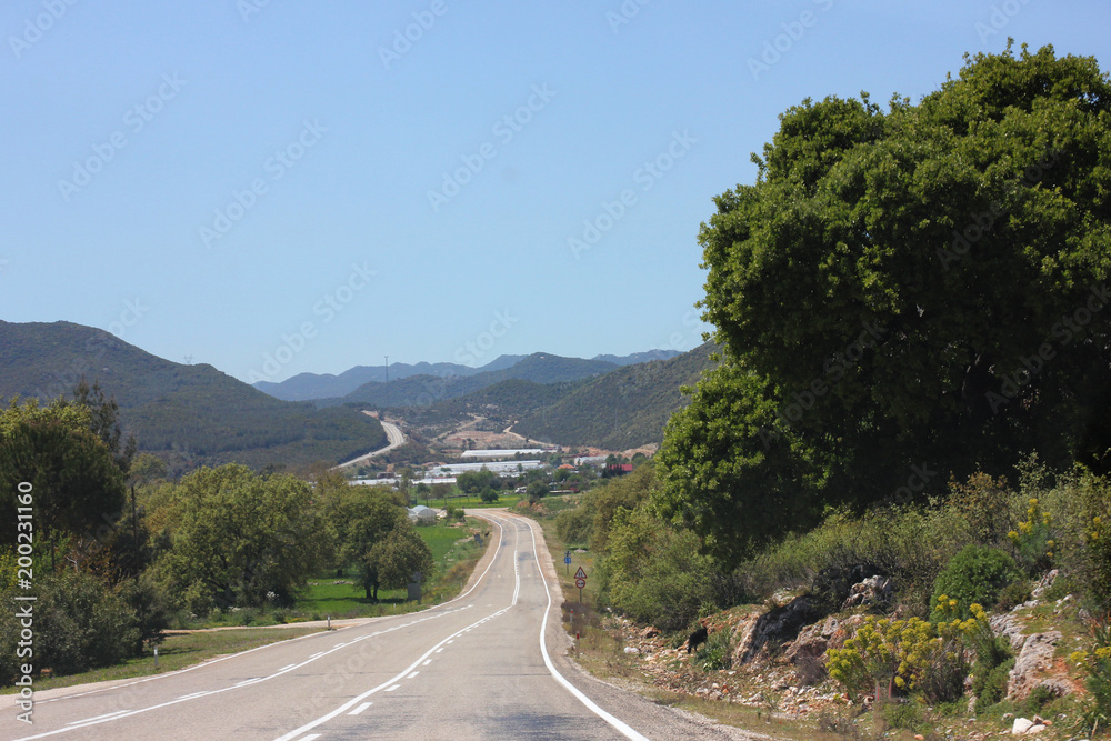 Narrow mountain asphalt road. Blue summer sky