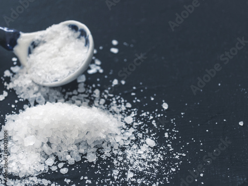 White salt in spoon on black background