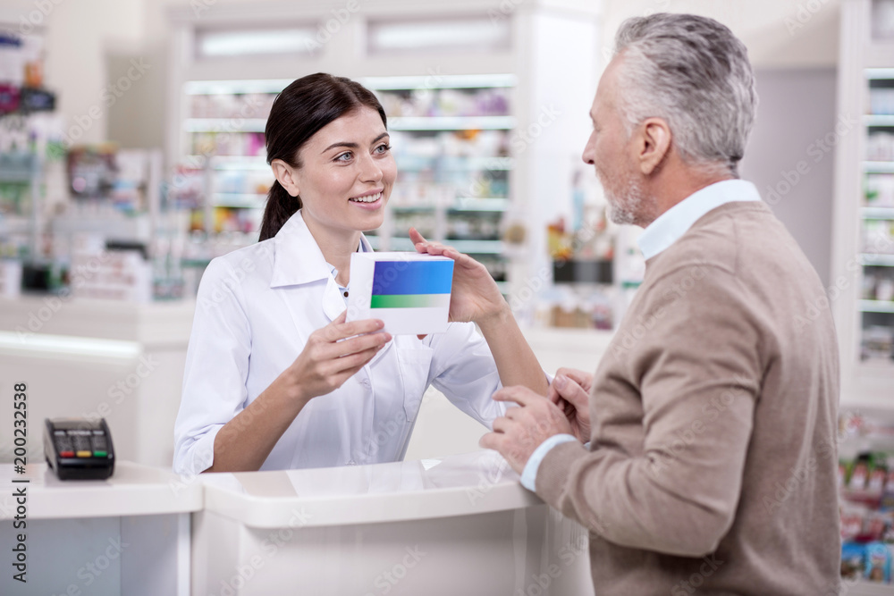 Effective medicine. Optimistic female pharmacist talking to mature man about side effect while carrying medication