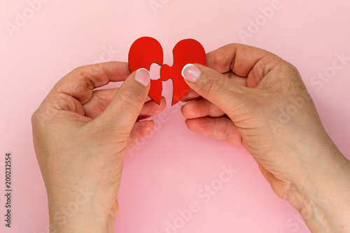 Two hand holding connecting two piece jigsaw love heart puzzle,love concept