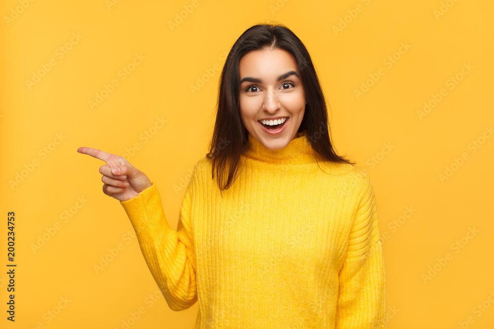Amazed brunette pointing away on yellow Amazed brunette pointing away on yellow