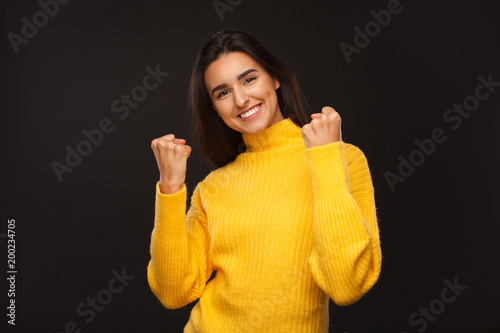Satisfied woman holding fists up on black