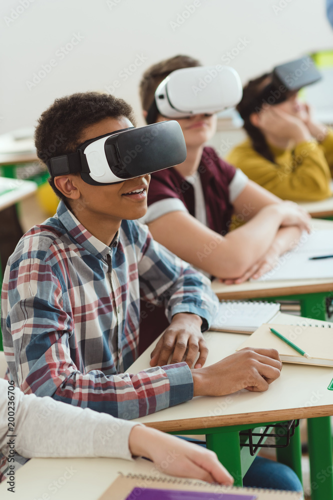 Naklejka premium Multiethnic high school students using virtual reality headsets in classroom