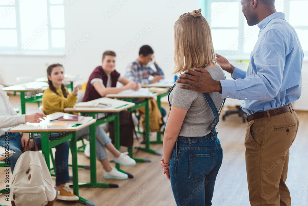 Fototapeta premium African american teacher introducing new girl to multicultural classmates