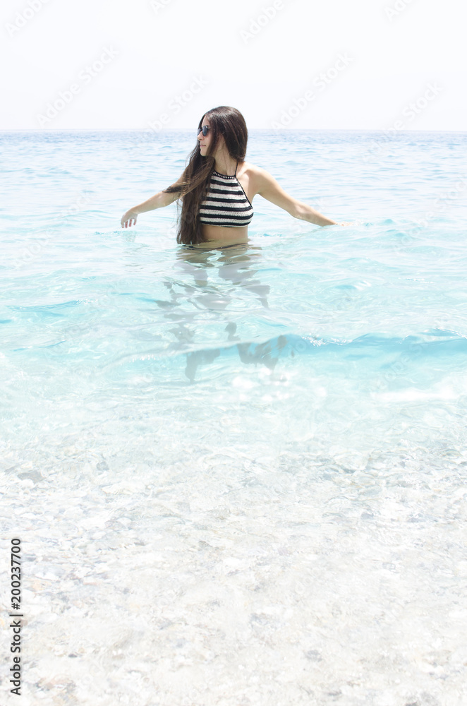 young woman swimming on a beach of clear blue water young woman swimming on a beach of clear blue water