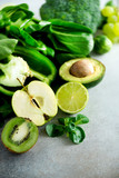 Organic green vegetables and fruits on grey background. Copy space. Green apple, lettuce, cucumber, avocado, kale, lime, kiwi, grapes, banana, broccoli
