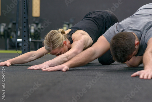 Man and woman stretching in a gym