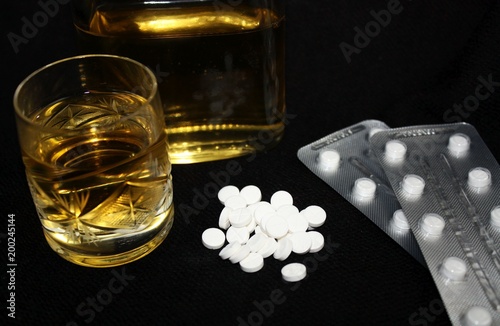 Drugs, blister, glass and bottle of alcohol. Benzodiazepines suicide combination or addiction narcotic concept.