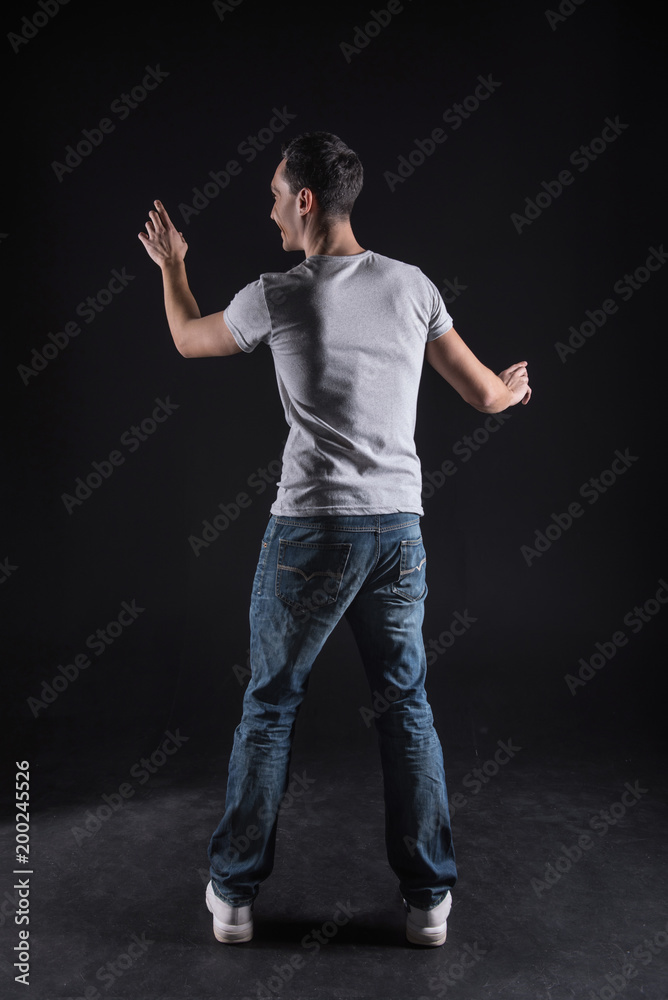 Technological device. Handsome good looking young man standing against black background and using modern computer screen while doing his work Technological device. Handsome good looking young man standing against black background and using modern computer screen while doing his work