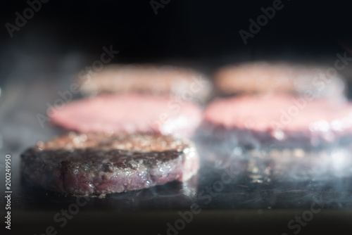 Hamburger cutlet frying on pan.Natural meet loaf pieces cooking in the kitchen.Burger sandwich meat being cooked with a lot of white smoke from a fat and oil. photo