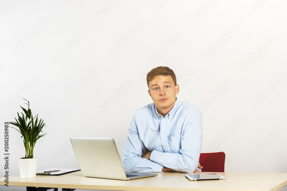 Happy young businessman using laptop at his office desk and smiling, look straight ahead. Happy young businessman using laptop at his office desk and smiling, look straight ahead.