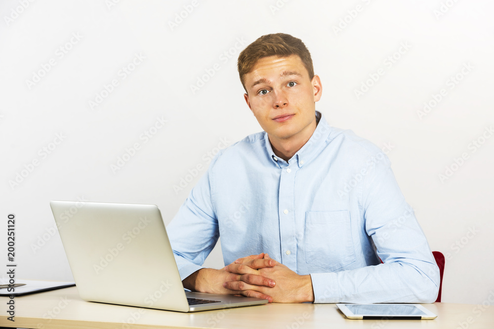 Happy young businessman using laptop at his office desk and smiling, look straight ahead. Happy young businessman using laptop at his office desk and smiling, look straight ahead.
