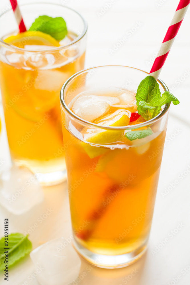 Glasses of iced tea with lemon slices and mint on white wooden background Glasses of iced tea with lemon slices and mint on white wooden background
