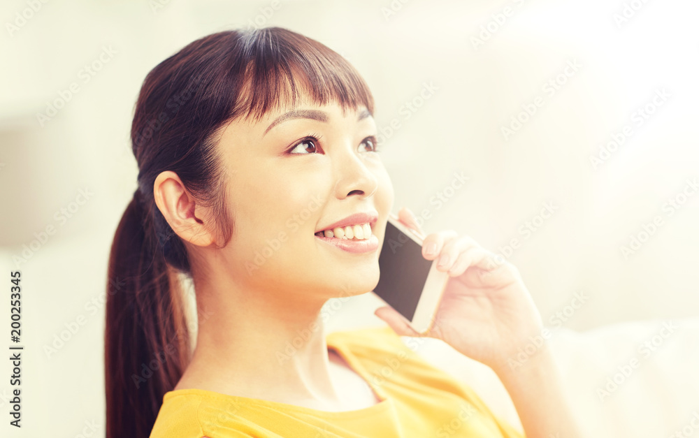 people, technology, communication and leisure concept - happy young asian woman calling on smartphone at home people, technology, communication and leisure concept - happy young asian woman calling on smartphone at home