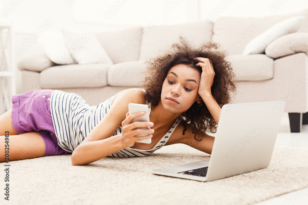 Young girl with laptop messaging on mobile
